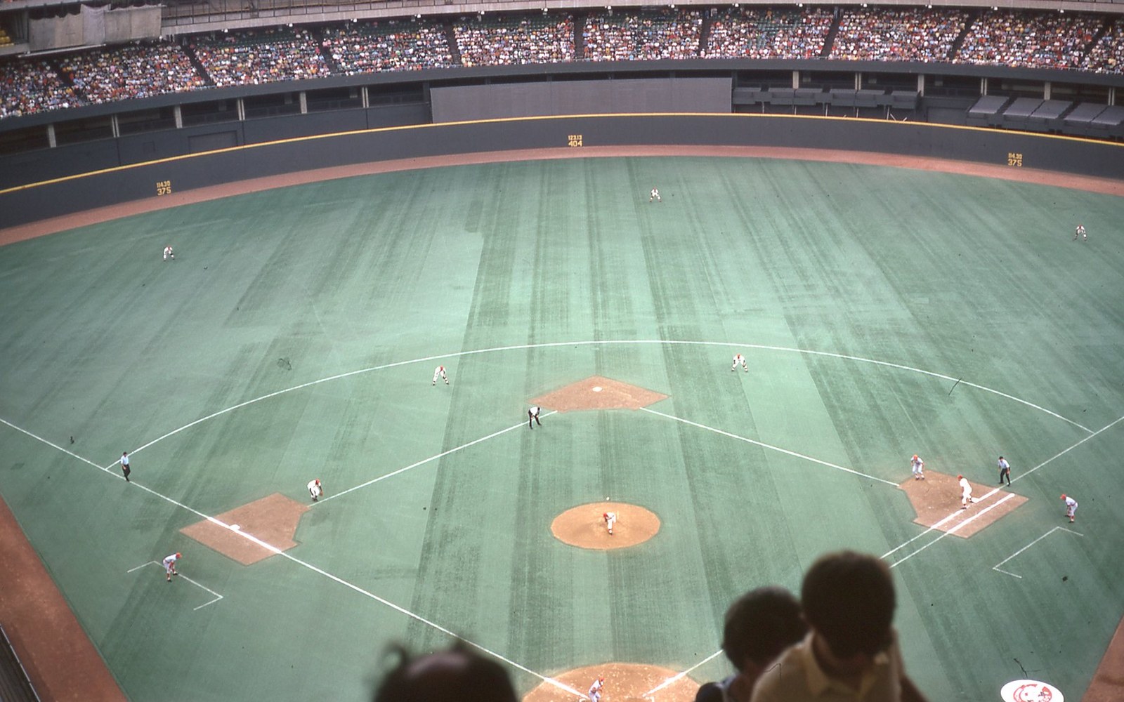 Aerial view of a baseball diamond mid-play inside a packed domed stadium