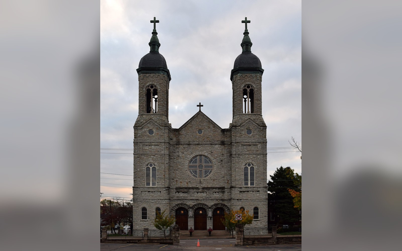 Twin-towered stone church facade with a rose window and triple entrance doors