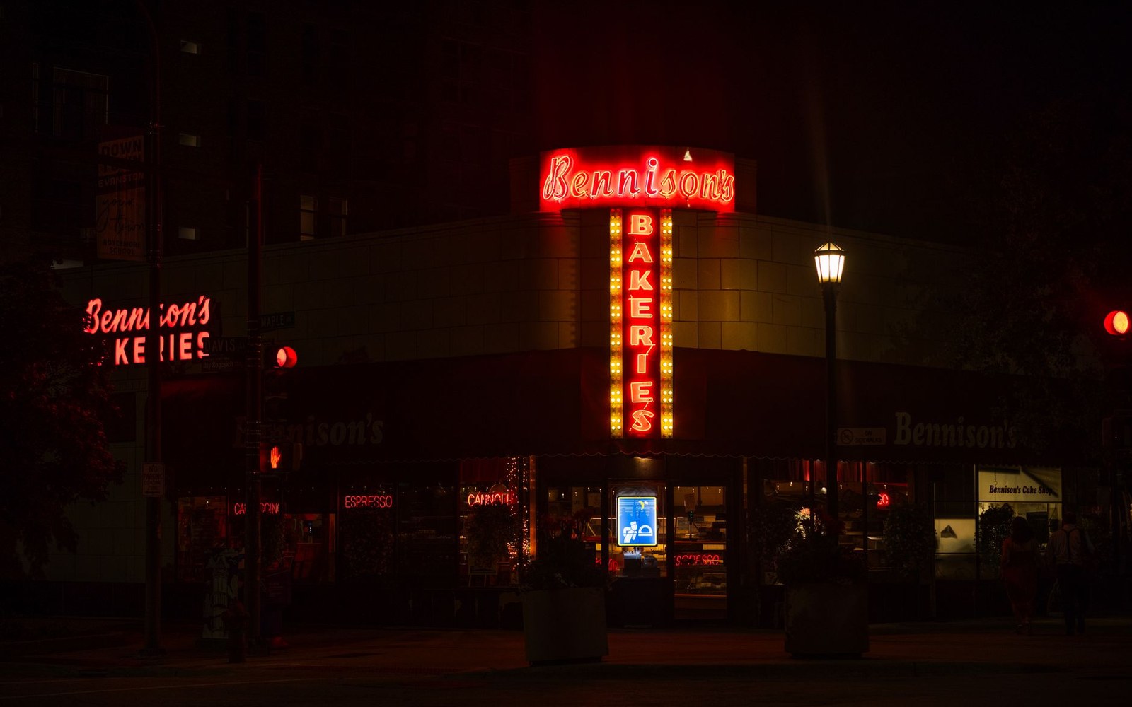Bennison's Bakeries corner storefront lit by a glowing red neon sign at night