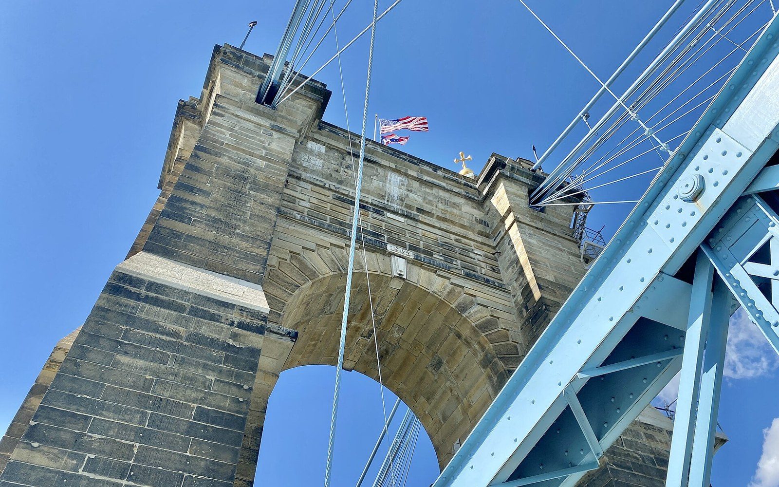 Suspension bridge tower viewed from below with cables and steel girders converging overhead