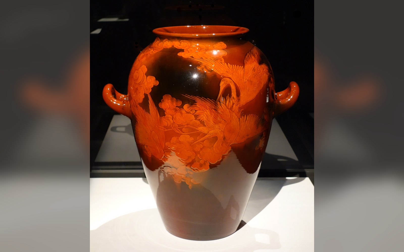 Glazed orange ceramic vase with handles, etched with bird and floral motifs